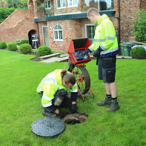 Two drain experts inspecting a blocked drain with a camera