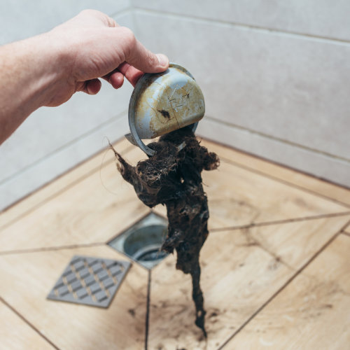 A blocked shower drain being unblocked