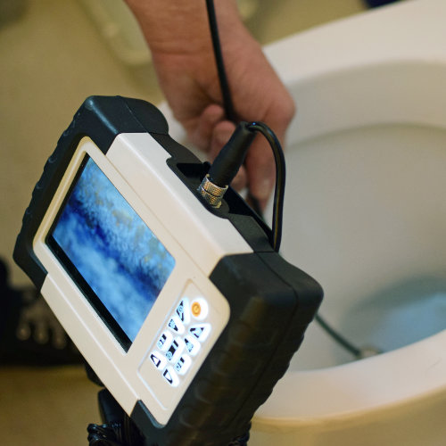 A drain expert inspecting a blocked toilet with a camera