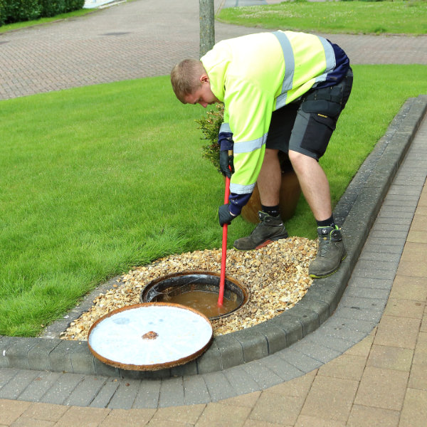 A drain cleaner working on an overflowing drain in a garden