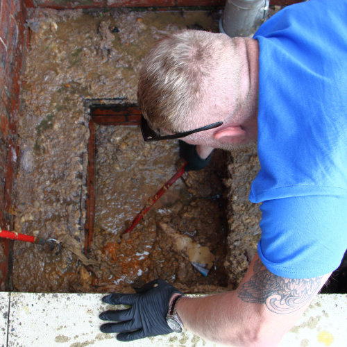 A drain clearance expert working on a totally blocked and overflowing outside drain