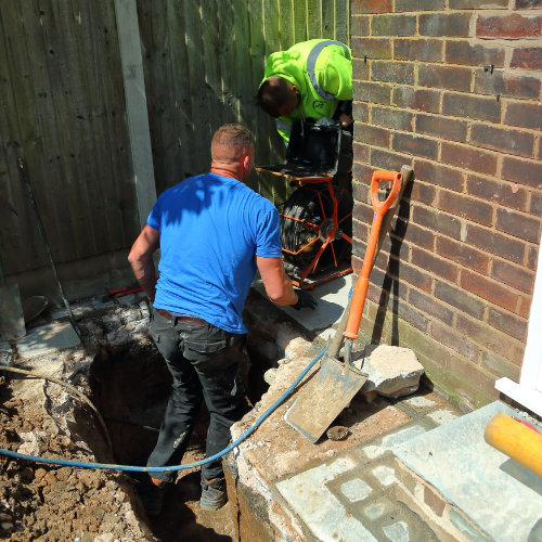 A drain being repaired by two drain specialists