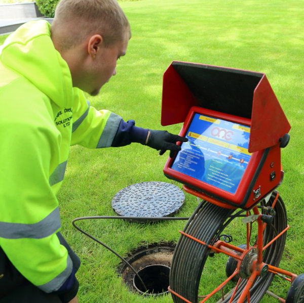 A drain expert looking at a screen on a drain survey system